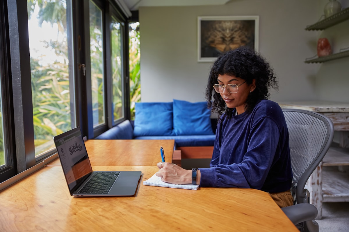 Someone taking notes beside a laptop while working