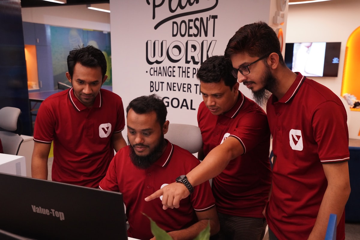 Four colleagues gathered around a screen, working through something together
